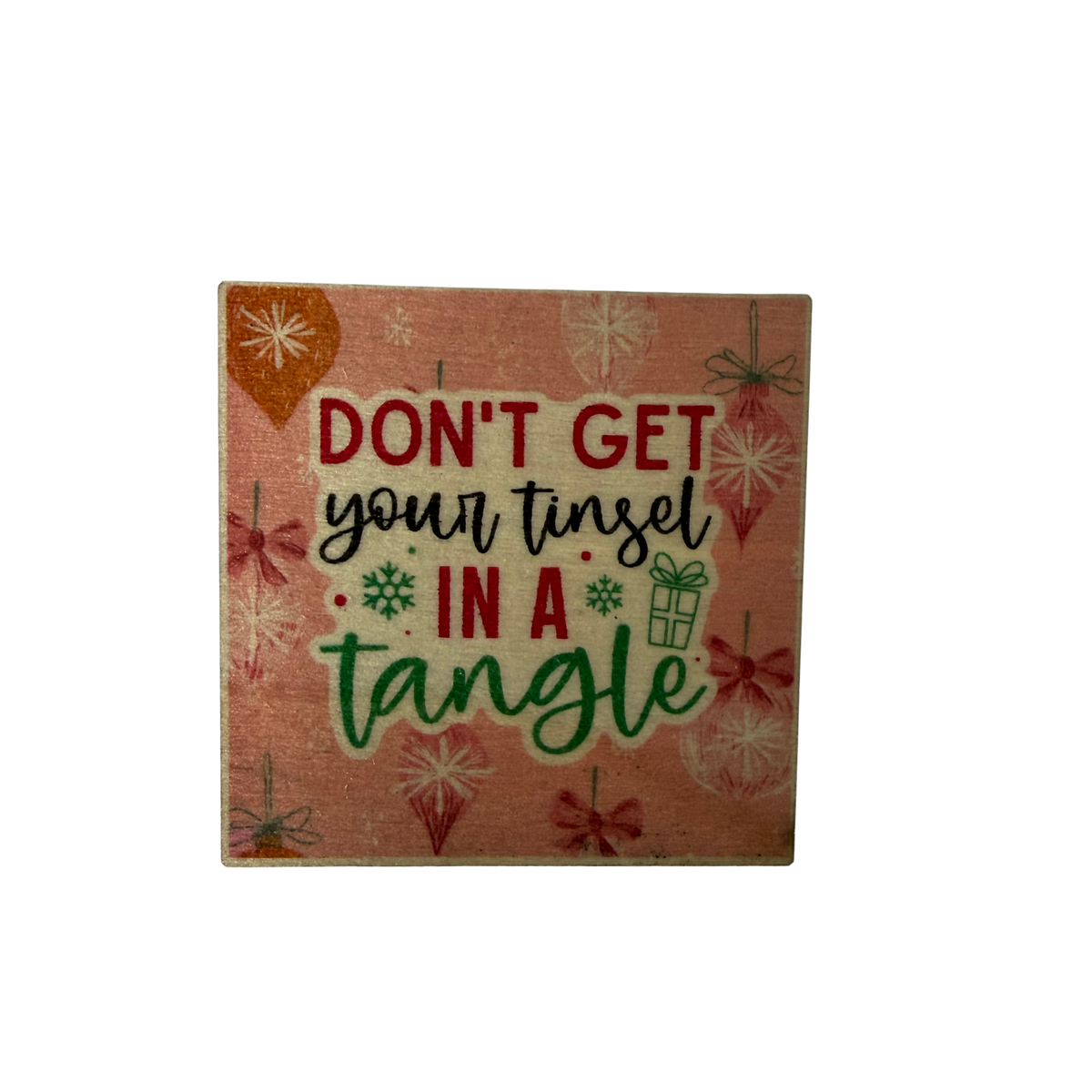 Square pink wooden Christmas magnet with Don't Get Your Tinsel in a Tangle lettering, baubles, bows and snowflakes.