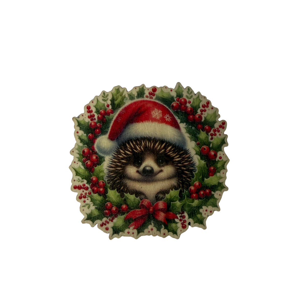 Wooden echidna Christmas magnet wearing a red Santa hat, surrounded by green foliage, red berries and a red bow on a white background.