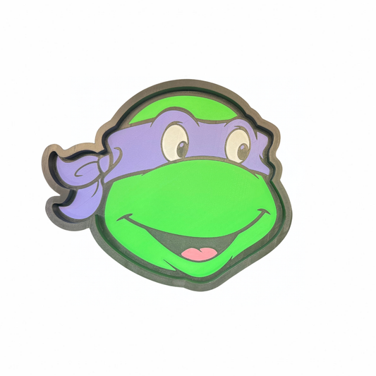 Purple and green Teenage Mutant Ninja Turtles character face-shaped trinket tray on a white background